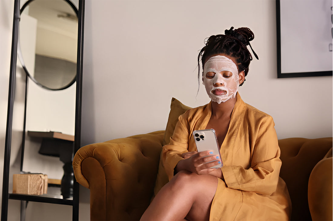 woman sitting on a coach with a face mask holding iphone